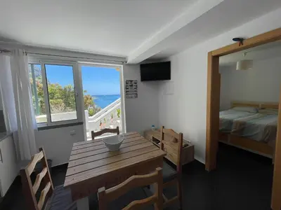 a room with a table and a bed and a window at MAKTUB SUNSET COTTAGE A in Paul do Mar