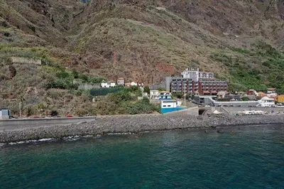 a town on the side of a mountain next to the water at MAKTUB SUNSET COTTAGE A in Paul do Mar