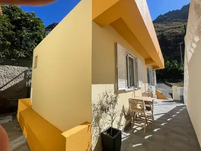 a yellow house with a table and chairs on a patio at MAKTUB SUNSET COTTAGE A in Paul do Mar