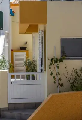 a building with a white door and a tv at MAKTUB SUNSET COTTAGE A in Paul do Mar