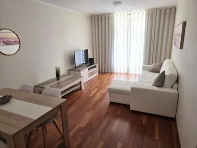 a living room with a white couch and a tv at Wings Apartment in Santa Cruz
