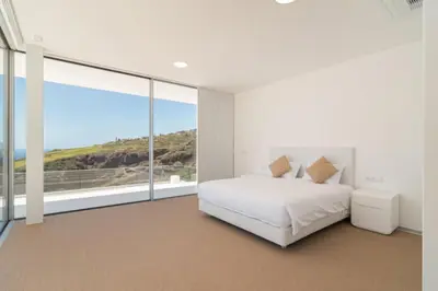 a bedroom with a white bed and a large window at Villa Camacho - Ultra Luxury in Calheta