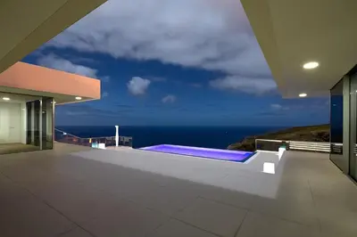 a swimming pool on the side of a house with the ocean at Villa Camacho - Ultra Luxury in Calheta