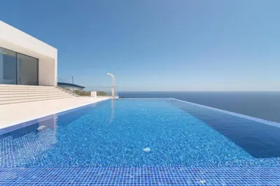 a swimming pool with blue water in front of a house at Villa Camacho - Ultra Luxury in Calheta