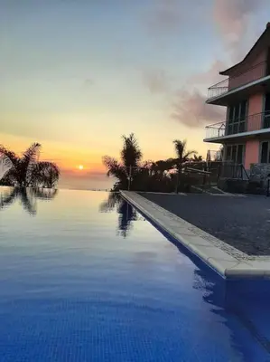a swimming pool with a sunset in the background at Ocean View Madeira 3 - Ponta do Sol in Canhas
