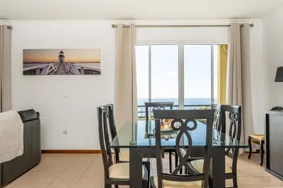 a dining room with a glass table and chairs at Bela Vista Sea View in Venda do Atalhinho