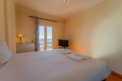 a bedroom with a large white bed with a window at FLH Garajau Fantastic Ocean View with Balcony in Funchal