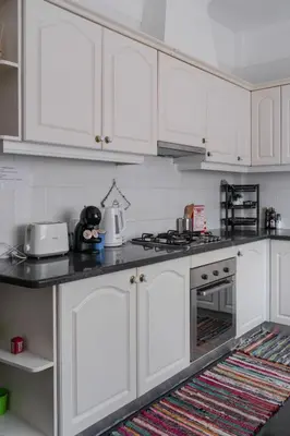 a white kitchen with white cabinets and a rug at Sunset House in Câmara de Lobos