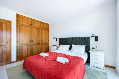a bedroom with a red bed with two towels on it at Apartment Henry Matisse, swimming pool in Sagres