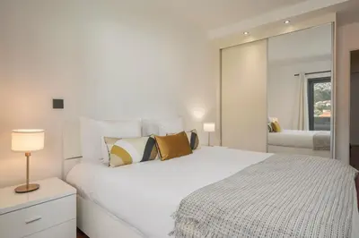 a white bedroom with a large bed and a mirror at Madalenas XXI by An Island Apart in Funchal