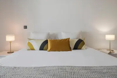a bedroom with a white bed with pillows and two lamps at Madalenas XXI by An Island Apart in Funchal