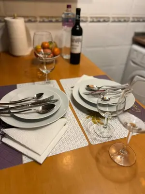 a wooden table with plates and silverware and a bottle of wine at Lagos Apartment Sea View in Lagos