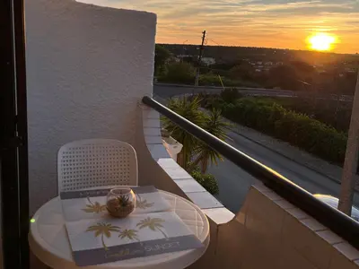 a table and chair on a balcony with the sunset at Lagos Apartment Sea View in Lagos