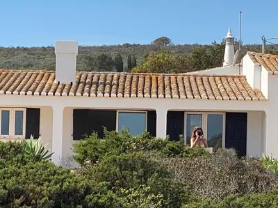 a woman taking a picture of a house at Tasi Ingrina in Vila do Bispo