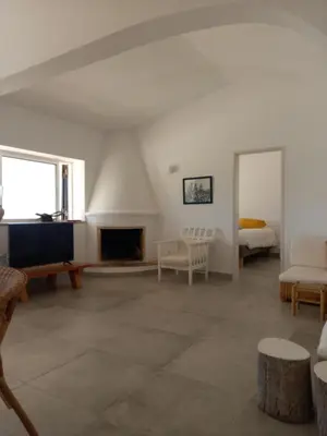 a living room with white walls and a fireplace at Tasi Ingrina in Vila do Bispo