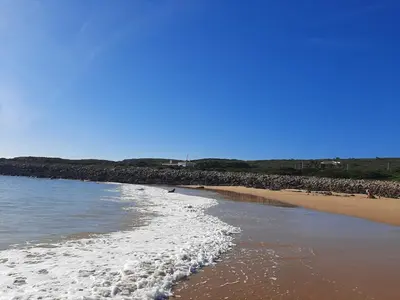 a beach with a group of people walking on the sand at Tasi Ingrina in Vila do Bispo