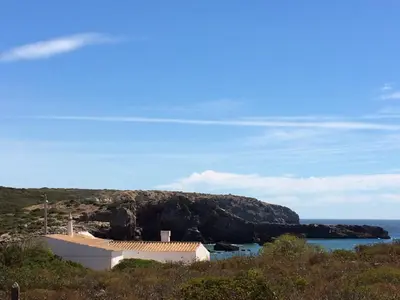 a house on a cliff with the ocean in the background at Tasi Ingrina in Vila do Bispo
