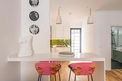 a kitchen with a white counter and pink chairs at Eva Boutique Apartment in Funchal