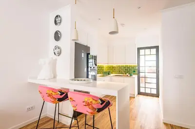 a kitchen with a white counter and two pink chairs at Eva Boutique Apartment in Funchal