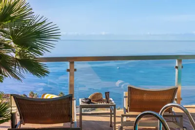 a balcony with chairs and a table with a view of the ocean at OurMadeira - Vista Grande in Caniço