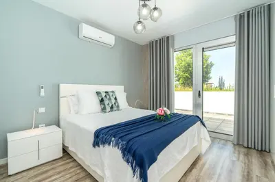 a white bedroom with a bed and a window at Casa Alan by Rent2u, Lda in Arco da Calheta