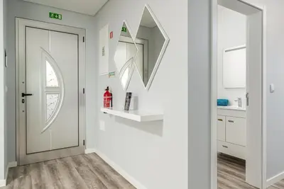 a white hallway with a door and a mirror at Casa Alan by Rent2u, Lda in Arco da Calheta