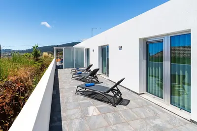 a row of chaise lounge chairs on a balcony at Casa Alan by Rent2u, Lda in Arco da Calheta