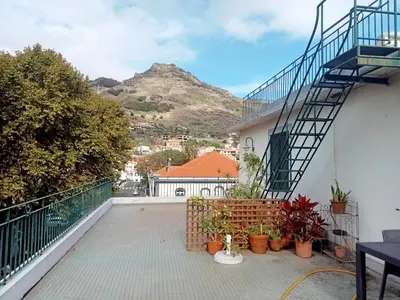 a balcony of a building with a staircase and a mountain at Machico Centre Comfort in Machico