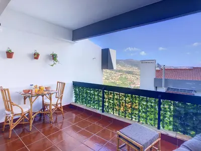 a balcony with a table and chairs and a large window at Casa Pico dos Barcelos by LovelyStay in Funchal
