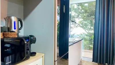 a kitchen with a microwave and a window at Studio Geek Villa - Open Space - 5m from 5 top attractions - Pool all year round, Dining Pergola, Barbecue - Funchal Matrix Holiday Home in Funchal