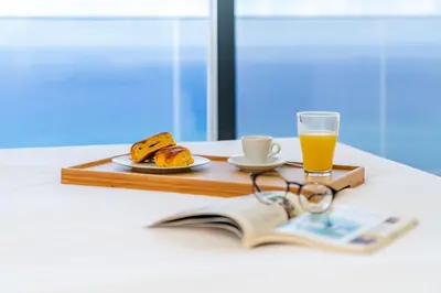 a tray with a book and a glass of orange juice at Villa Candelária by An Island Apart in Ribeira Brava