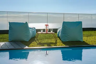 a patio with a table and pillows next to a pool at Villa Candelária by An Island Apart in Ribeira Brava
