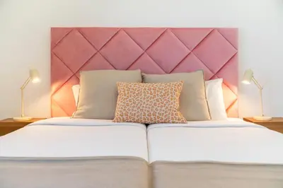 a white bed with a pink headboard and two lamps at Villa Candelária by An Island Apart in Ribeira Brava