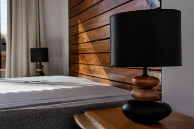 a black lamp on a wooden table next to a bed at CASA DA PITANGA in Jardim do Mar