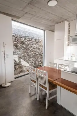 a kitchen with a wooden table and white chairs at CASA DA PITANGA in Jardim do Mar