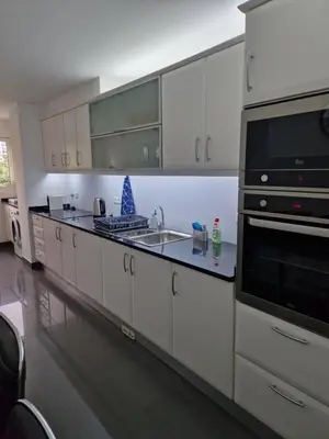 a kitchen with white cabinets and a sink and a microwave at Cristinas 2 Bedroom Apartment Caniço in Caniço