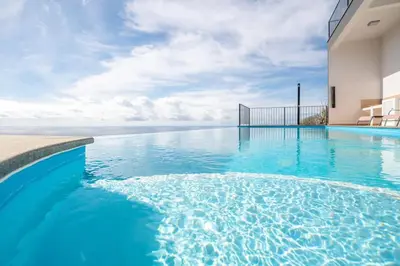a swimming pool in a house with blue water at Marina View Apartment - Pool & stunning ocean view in Calheta