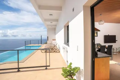 a view from the balcony of a house with a swimming pool at Marina View Apartment - Pool & stunning ocean view in Calheta