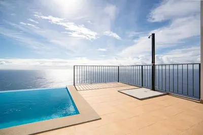 a balcony with a swimming pool and the ocean at Marina View Apartment - Pool & stunning ocean view in Calheta