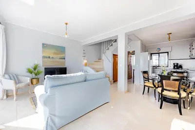 a living room with a white couch and a dining room at Bay View Townhouse in Salema