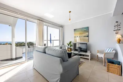 a living room with a couch and a television at Bay View Townhouse in Salema