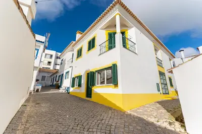 a yellow and white building on a cobblestone street at Villa som das Ondas in Budens