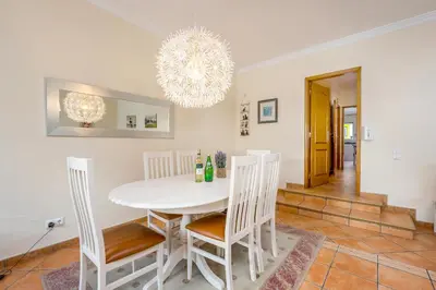 a dining room with a white table and chairs at Villa som das Ondas in Budens