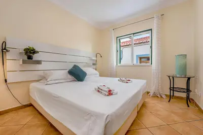 a bedroom with a white bed with two towels on it at Villa som das Ondas in Budens