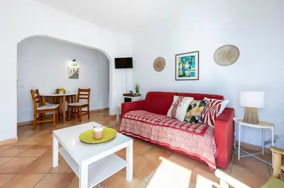 a living room with a red couch and a table at Villa som das Ondas in Budens