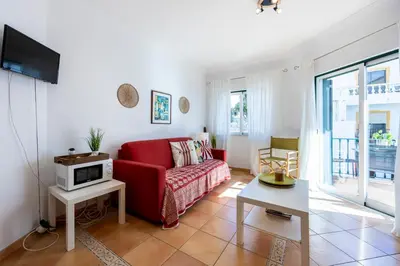 a living room with a red couch and a tv at Villa som das Ondas in Budens