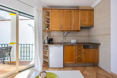 a kitchen with wooden cabinets and a white refrigerator at Villa som das Ondas in Budens