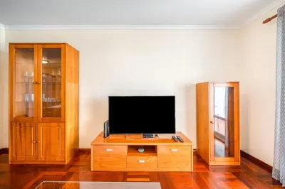 a living room with a television on a wooden cabinet at Apartamento Vista Azul in Funchal