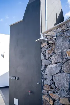 a stone building with a black door and a stone wall at Majestic Seaview Villa in Fajã da Ovelha