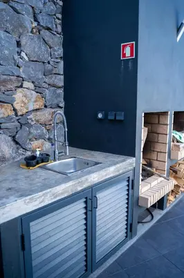 a kitchen with a sink and a stone wall at Majestic Seaview Villa in Fajã da Ovelha